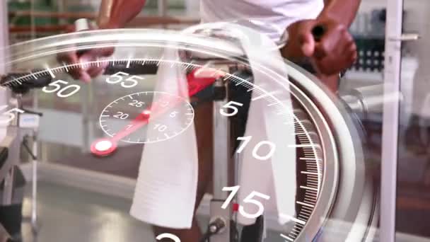 Stopwatch graphic over man using exercise bike — Stock Video