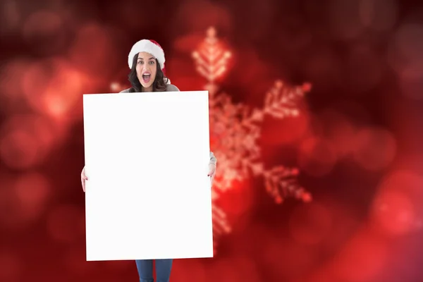 Composite image of happy brunette in santa hat showing white pos — Stock Photo, Image