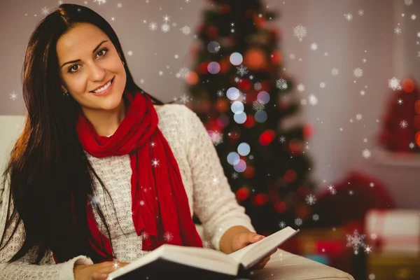 Pretty brunette reading on couch at christmas — Stock Photo, Image
