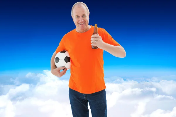 Reifer Mann im orangefarbenen T-Shirt hält Fußball in der Hand — Stockfoto
