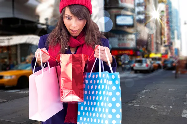 Shocked brunette opening gift bag — Stock Photo, Image