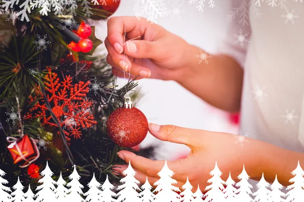 Frau hängt Weihnachtsschmuck an Baum — Stockfoto