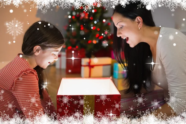 Festive madre e figlia che aprono un incandescente — Foto Stock