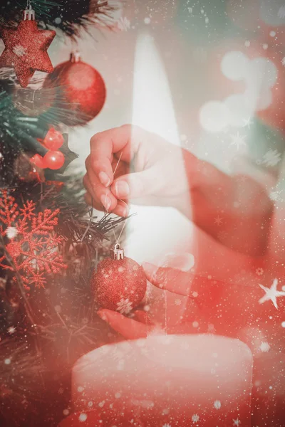 Frau hängt Weihnachtsschmuck an Baum — Stockfoto