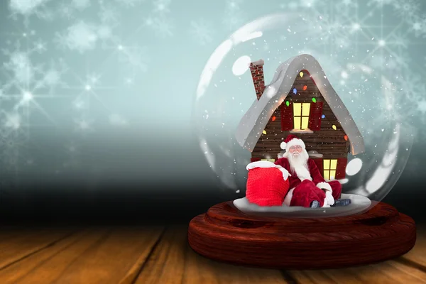 Санта сидит в снежном глобусе — стоковое фото