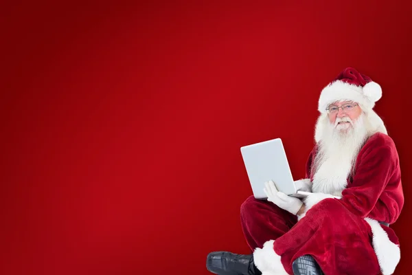 Santa sits and uses a laptop — Stock Photo, Image