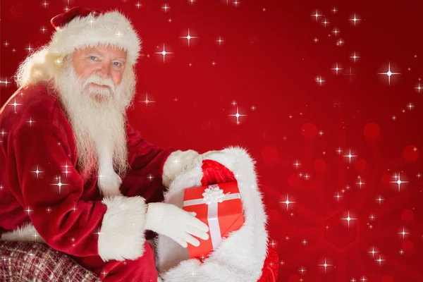 Father christmas taking red gift in bag — Stock Photo, Image