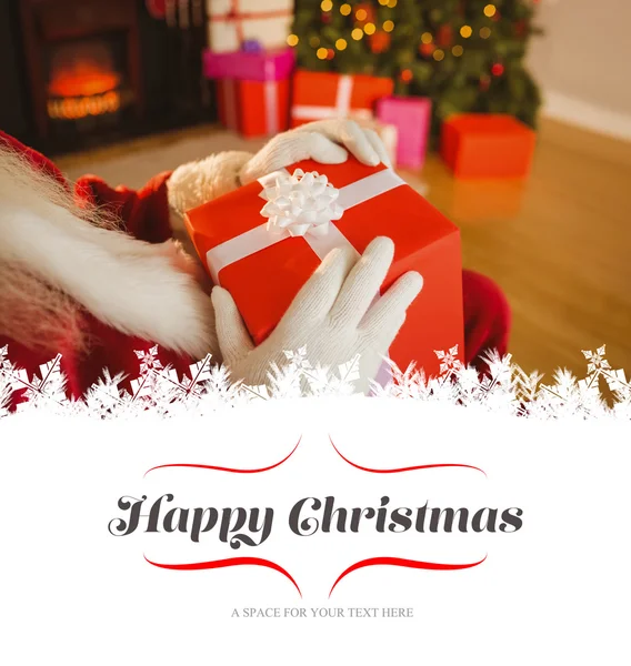 Санта-Клаус держит красный подарок — стоковое фото