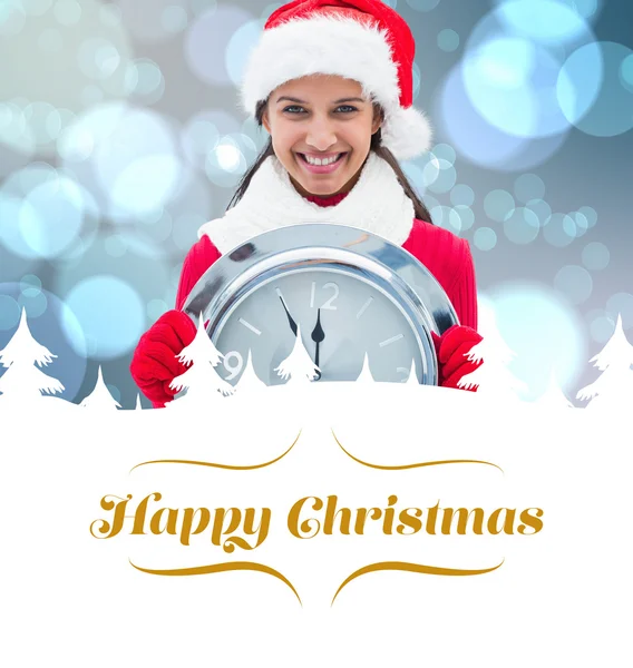 Composite image of festive brunette holding clock — Stock Photo, Image