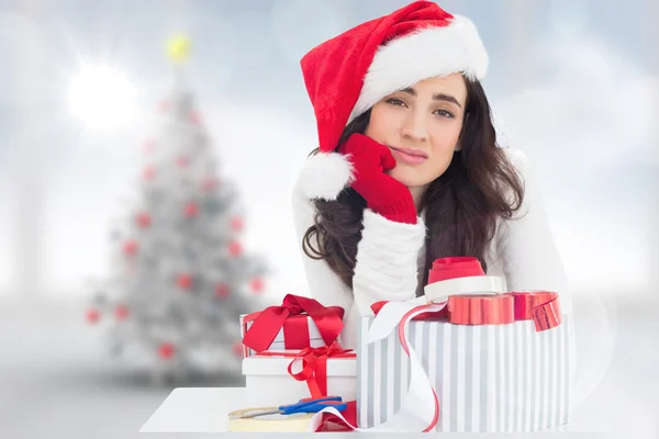Osäker på brunett i santa hatt packning gåvor — Stockfoto