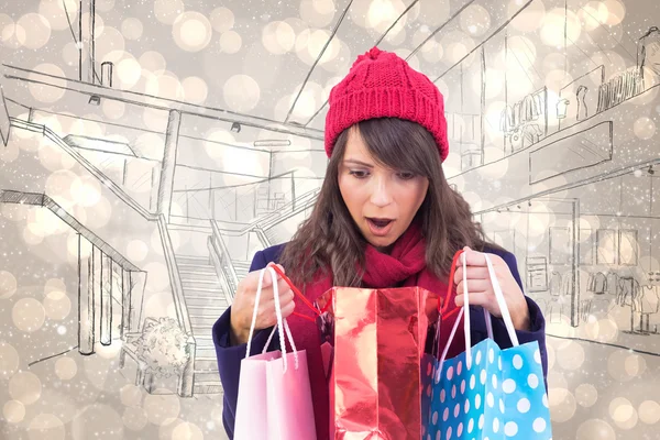 Shocked brunette opening gift bag — Stock Photo, Image