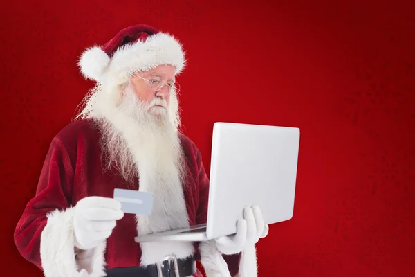 Santa platí kreditní kartou na laptop — Stock fotografie