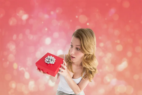 Composite image of surprised woman holding a gift — Stock Photo, Image