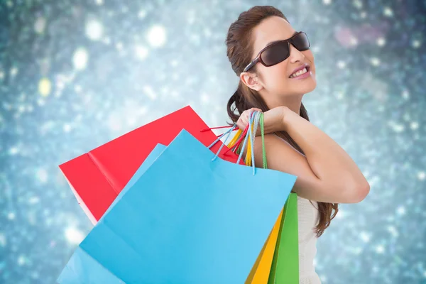 Composite image of brunette posing and holding shopping bags — Stock Photo, Image