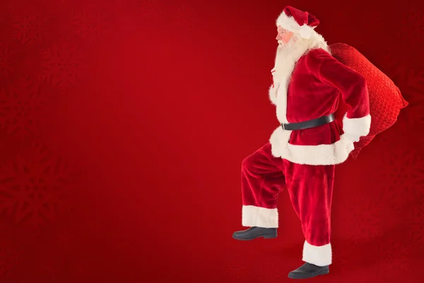 Composite image of santa jumps with his bag — Stock Photo, Image
