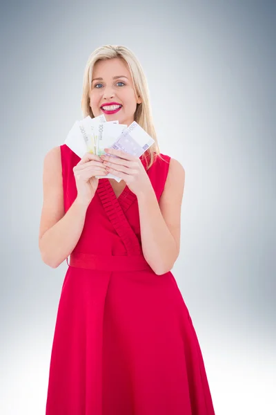 Blondynka w czerwonej sukience gospodarstwa pieniężnych — Zdjęcie stockowe