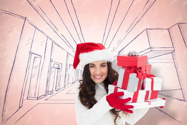 Festive brunette in santa hat holding pile — Stock Photo, Image