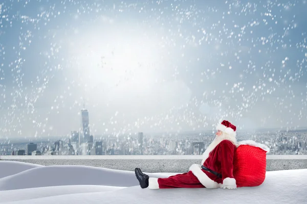 Papai Noel senta-se apoiado em sua bolsa — Fotografia de Stock