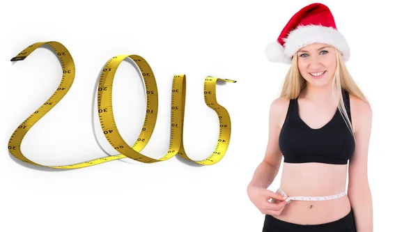 Composite image of fit festive young blonde measuring her waist — Stock Photo, Image