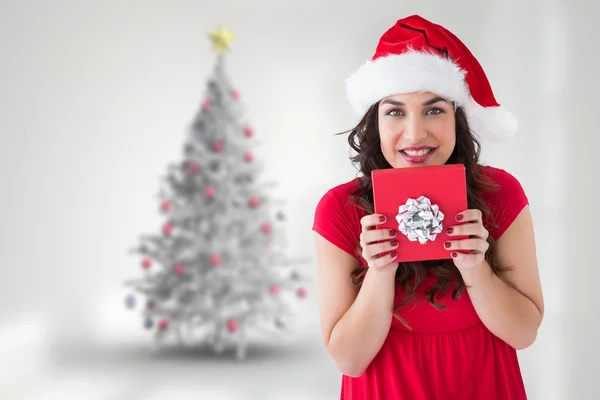 Composite image of festive brunette holding gift with bow — Stock Photo, Image