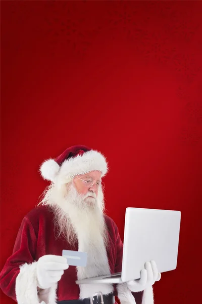 Santa platí kreditní kartou na laptop — Stock fotografie