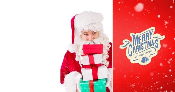 Smiling santa holding pile of gifts — Stock Photo, Image