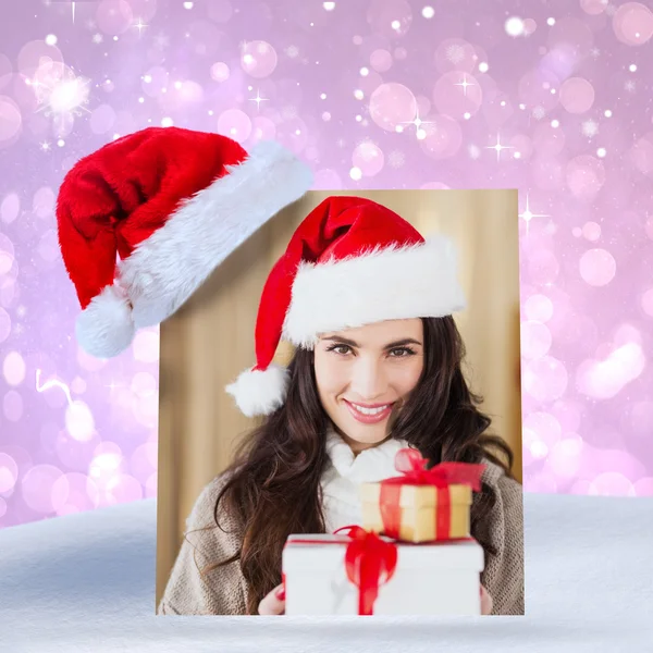 Festive brunette in santa hat holding gifts — Stock Photo, Image