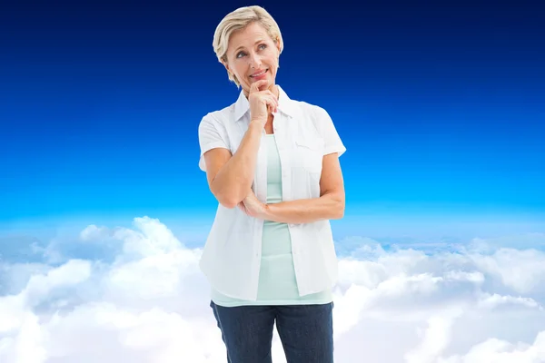 Happy mature blonde thinking with hand on chin — Stock Photo, Image