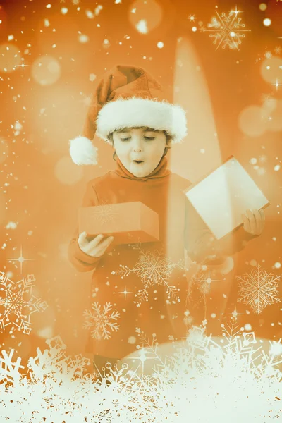 Zusammengesetztes Bild eines festlichen kleinen Jungen, der ein Geschenk öffnet — Stockfoto