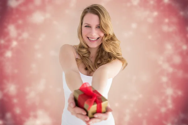 Composite image of smiling blonde offering a small gift — Stock Photo, Image