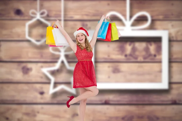 Pretty woman in santa hat holding up shopping — Stock Photo, Image