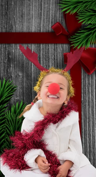 Composite image of cute little girl wearing red nose and tinsel — Stock Photo, Image