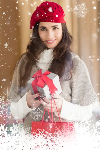 Sonriente morena sosteniendo regalo y bolsas de compras —  Fotos de Stock