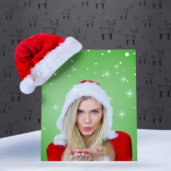 Composite image of pretty girl in santa outfit blowing — Stock Photo, Image