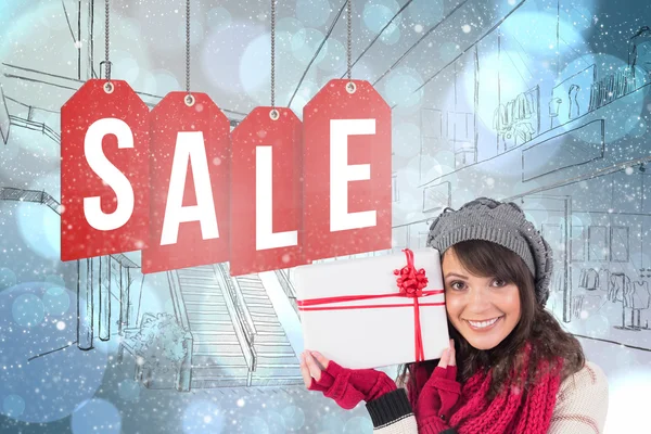 Composite image of festive brunette holding white and red gift — Stock Photo, Image