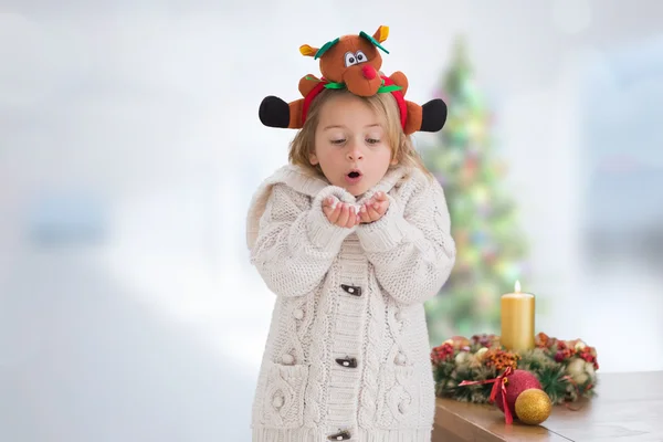 Composite image of cute girl blowing over hands — Stock Photo, Image