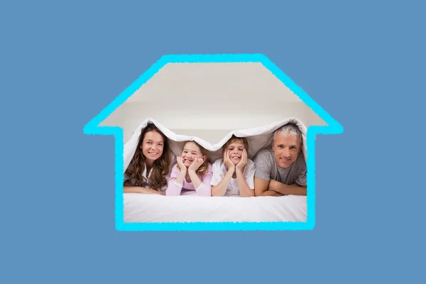 Speelse familie liggen onder een dekbed — Stockfoto
