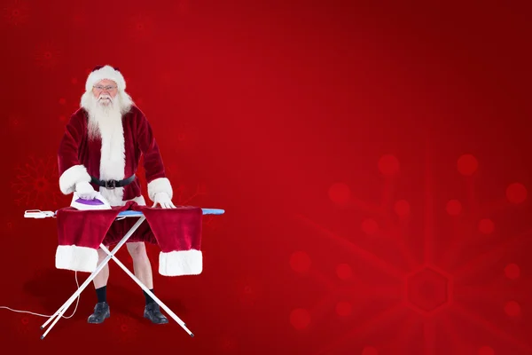 Lächelnder Weihnachtsmann bügelt seine Hosen — Stockfoto