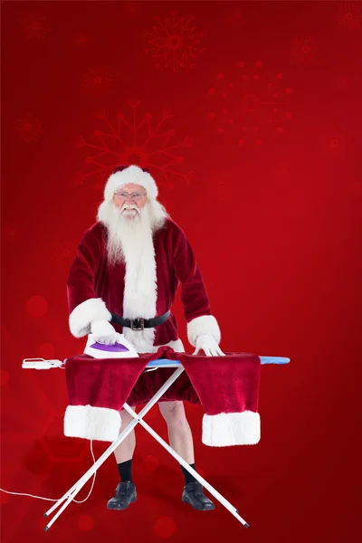 Smiling santa ironing his pants — Stock Photo, Image