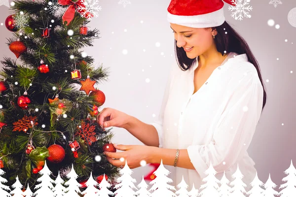 Woman hanging christmas decorations on tree — Stock Photo, Image