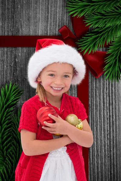 Imagem composta de menina bonito vestindo chapéu de santa segurando ba — Fotografia de Stock