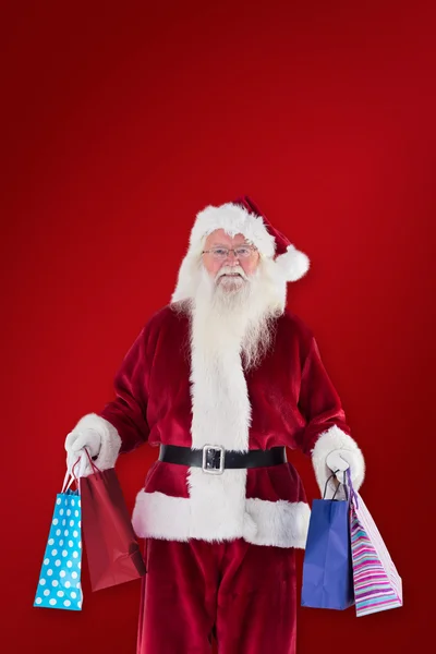 Imagen compuesta de santa lleva algunas bolsas de Navidad — Foto de Stock