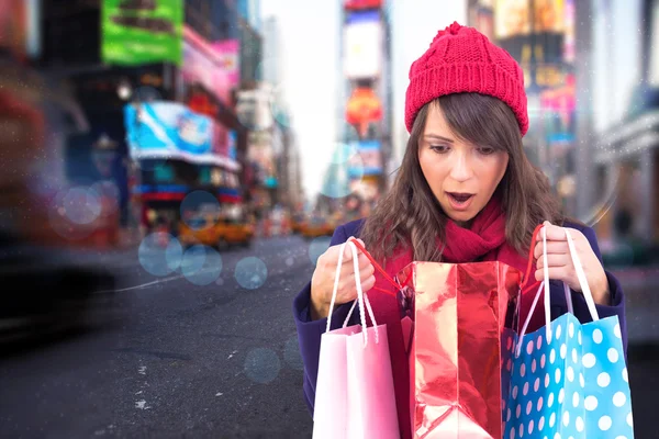 Shocked brunette opening gift bag — Stock Photo, Image