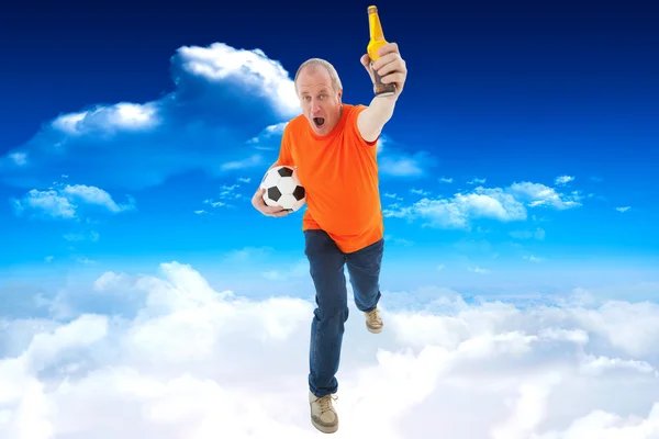 Reifer Mann im orangefarbenen T-Shirt hält Fußball in der Hand — Stockfoto