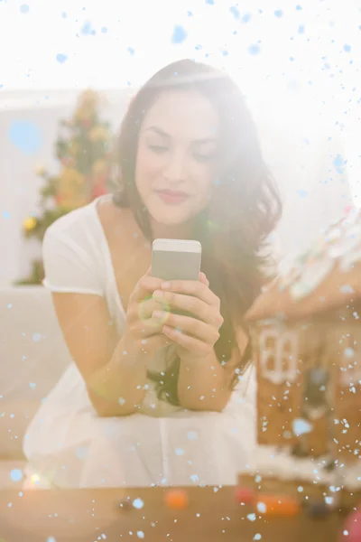 Brunette using her smartphone on sofa — Stock Photo, Image