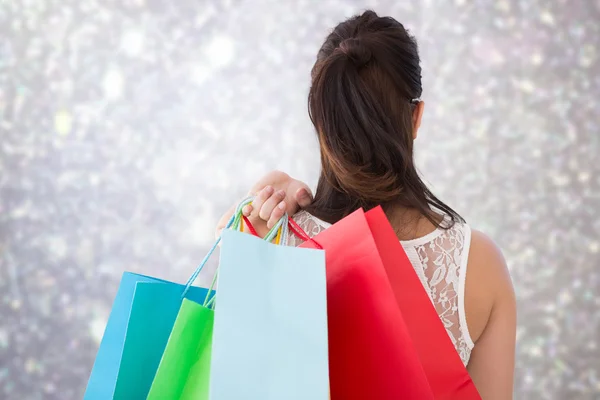 Imagem composta de visão traseira de morena segurando sacos de compras — Fotografia de Stock