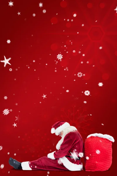 Weihnachtsmann sitzt auf Tasche gestützt — Stockfoto