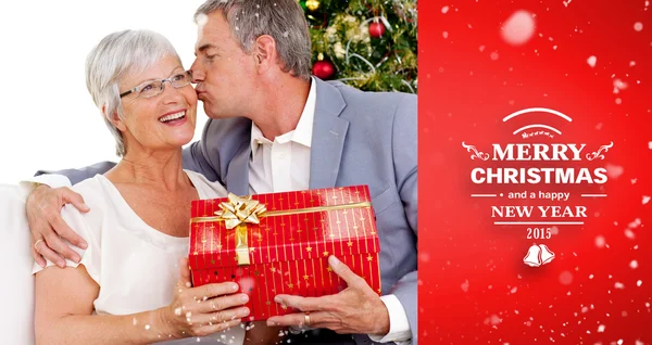 Senior man giving a kiss and a christmas present — Stock Photo, Image