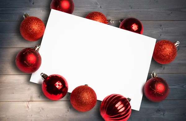 Imagem composta de bugigangas de Natal vermelho em torno de página branca — Fotografia de Stock