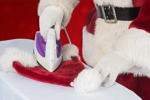 Father Christmas is ironing his hat — Stock Photo, Image